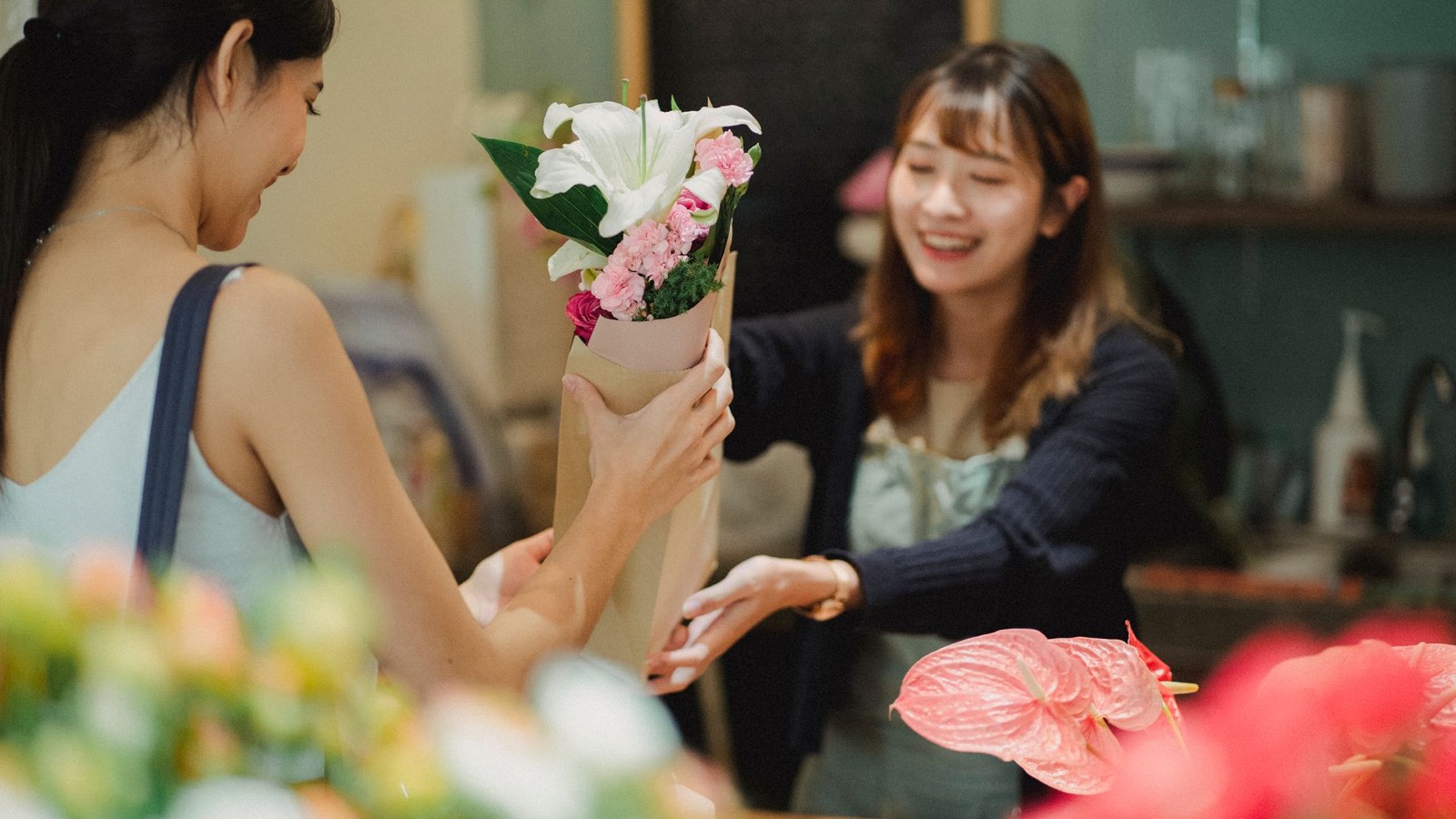A florist handing a bouquet to a customer across the counter